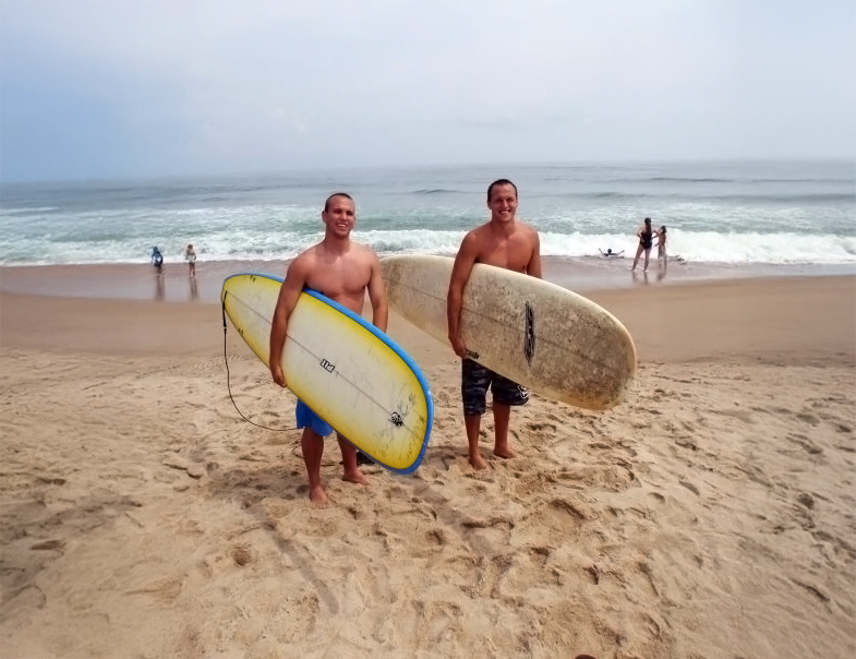 Two brothers standing on the beach holding surfboards in Kitty Hawk, North Carolina